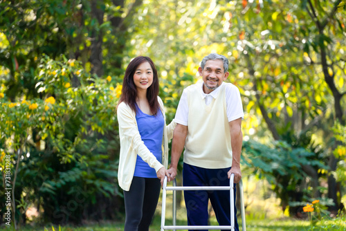 portrait young asian woman caregiver takes disability senior man practice walking with walker in the park