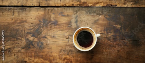 Morning time sees the placement of warm coffee atop a wooden surface.