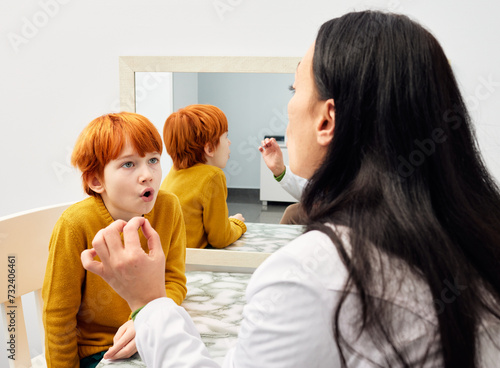 Treatment of stuttering in children. Speech and language therapist doing articulation and breathing exercises with boy patient