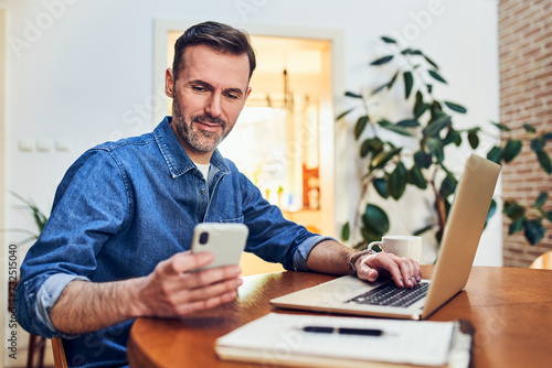 Man paying with 2FA two factor authentication using his phone and laptop at home