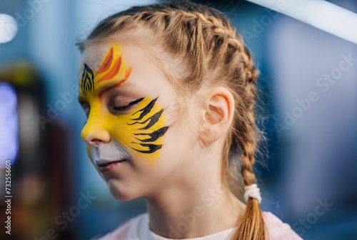 Photograph, portrait of a beautiful painted girl, a child with tiger face painting, makeup on her face.