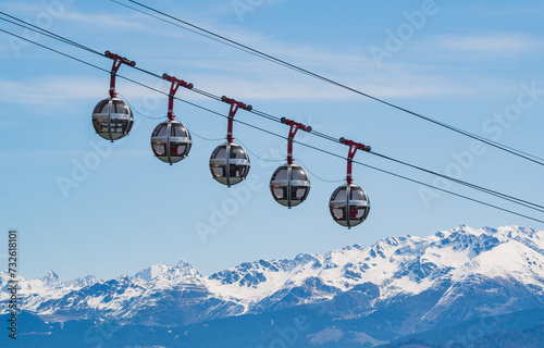 Gondola bubbles against the blue sky and the French Alps in the background. Cable car taking tourists to Fort de La Bastille in Grenoble, France