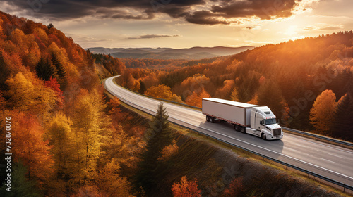 White truck driving on winding highway through woodland landscape in autumn colors at sunset