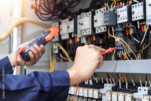 Electrician measurements with multimeter testing current electric in control panel. 
