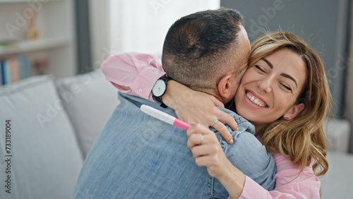 Man and woman couple holding pregnancy test celebrating at home