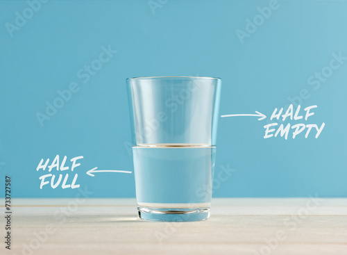 Optimism and Pessimism concept. Water glass with the words half full and half empty.