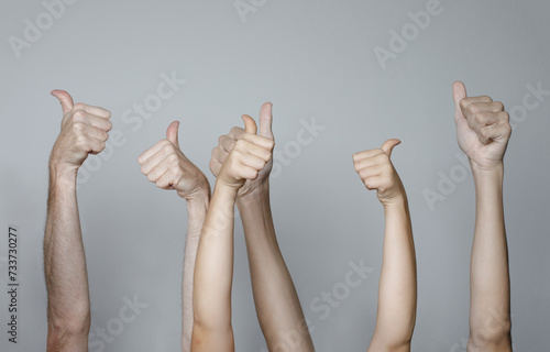 Close-up Of People's Hand Showing Thumb Up Sign Gesture on Gray Background