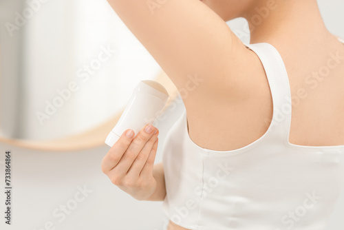 Beautiful woman applying deodorant in bathroom, closeup