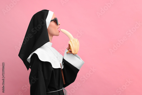 Woman in nun habit with banana against pink background, space for text. Sexy costume