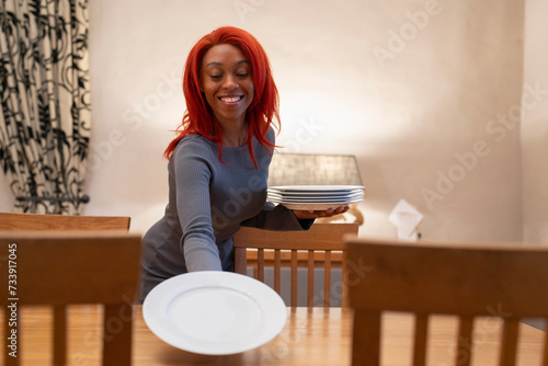 Smiling redhead woman setting table for dinner