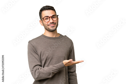 Young handsome caucasian man over isolated background presenting an idea while looking smiling towards