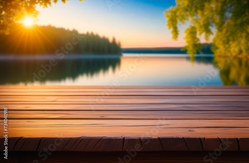 Empty wooden table with copy space for product presentation, against the backdrop of a summer lake and the setting sun.