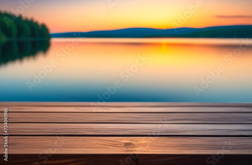 Empty wooden table with copy space for product presentation, against the backdrop of a summer lake and the setting sun.