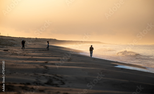 Gente na praia ao nascer do sol