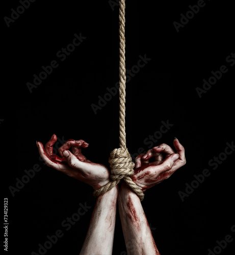 Woman hands with bloody stains tied with a rope over black background