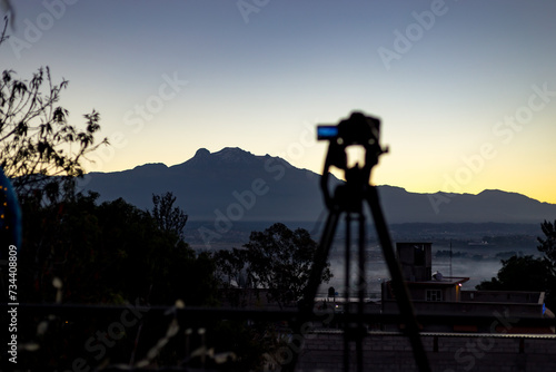 Fotografa esperando, contemplando el solsticio de invierno con los volcanes mexicanos en el amanecer del invierno de diciembre. Iztaccihuatl y Popocatepetl. México.