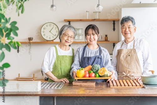 野菜を持つ高齢者夫婦と若い日本人（栄養士・家事代行・介護） 