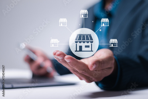 Franchise business concept. Person use laptop and hand holding store icon on virtual screen for franchise marketing system in global network connection.