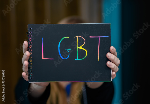 Kobieta trzyma kartkę z kolorowym napisem LGBT