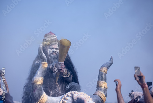 Masan Holi, Portrait of an male artist act as lord shiv with dry ash on face and body also in air while celebrating the holi festival as tradition at Harishchandra ghat in varanasi, India.
