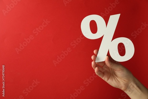Woman holding percent sign on red background, closeup. Space for text