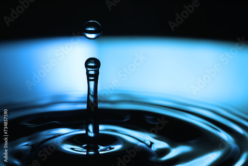 Droplet of water macro view. Drop of liquid falling on a blue black water surface. macro view