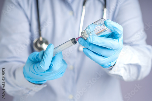 Doctor holding a syringe and vial with medication for injection.