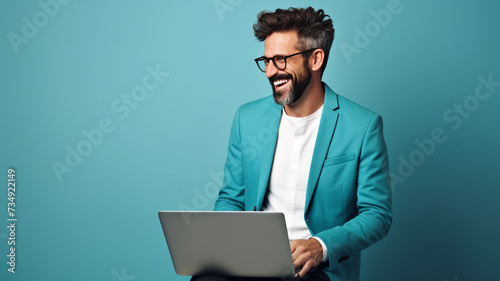 man sitting and smiling with laptop on blue background