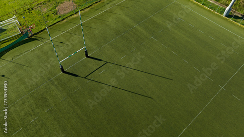 Aerial view of rugby goal post in a stadium on a sunny day. It is an artificial turf rugby field. The sports facility is empty.