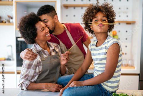 Overjoyed young african american family with kid have fun cooking at home together,