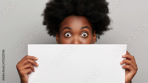 Mulher afro-americana surpresa espiando por trás de um outdoor em branco