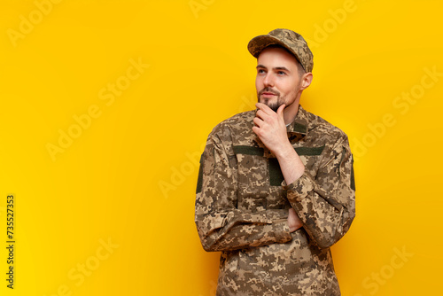 pensive ukrainian army soldier in camouflage uniform pixel plans and thinks on a yellow isolated background, ukrainian military cadet dreams and imagines