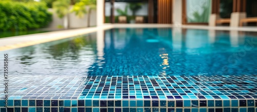 Tranquil blue tile pattern pool surrounded by lush greenery and illuminating natural sunlight