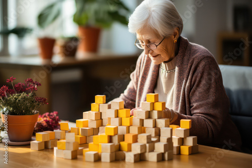 Elderly woman with dementia playing with wooden blocks in geriatric clinic or nursing home.