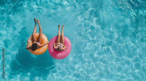 An wonderful summer vacation with a high view from above, showing a mother and her little child lounging on donut lilo in the private villa pool.