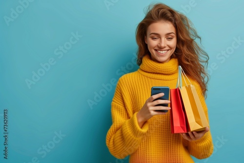A smiling young woman on a blue background with a phone in her hands and a grocery bag. Online shopping in an online store