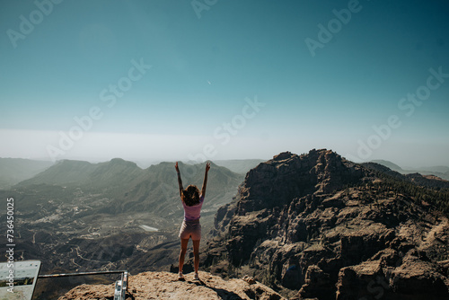 Turystka z podniesionymi rękoma na szczycie góry na wyspie Gran Canaria