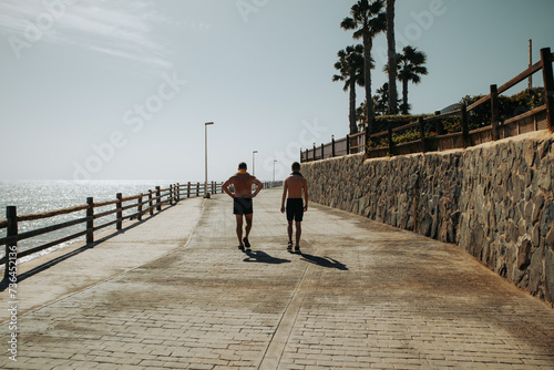 Turyści spacerują promenadą w słoneczny dzień, Bahia Feliz, Gran Canaria, Hiszpania
