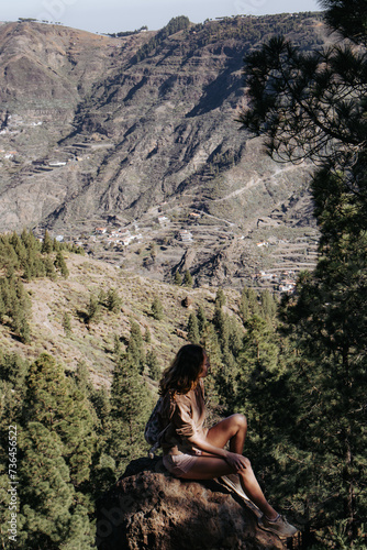 Turystka siedzi na kamieniu w cieniu na tle gór, Gran Canaria, Hiszpania