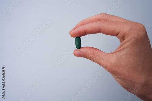 hand with pills green chlorophyll