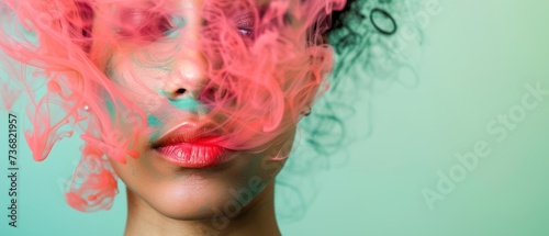 a close up of a woman's face with pink and blue smoke coming out of her face and her hair blowing in the wind.