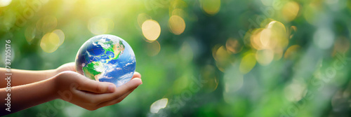 International human solidarity day concept. Children hands holding earth globe over blurred abstract green nature background. saving planet, environment ecology concepts.Banner,advertisement.