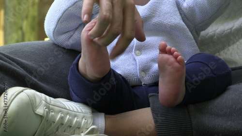 Mother tickling baby foot infant with mom