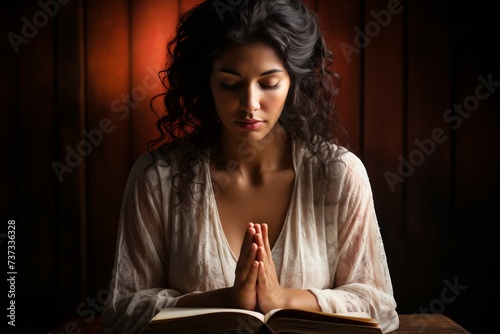 Praying woman with dark hair wearing white dress