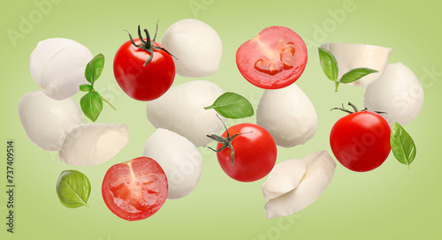 Ingredients for Caprese salad. Mozzarella balls, basil and tomatoes falling on green background, banner design