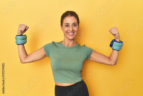 Sportswoman with wrist weights in yellow studio