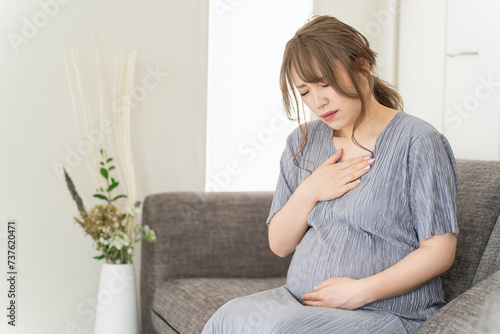 家のソファに座る妊婦・マタニティ（胸焼け・気持ち悪い・妊娠後期） 