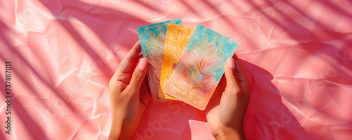 Hands holding 3 beautiful tarot and oracle card on pink background, inviting users to seek guidance, self-reflection, and spiritual insights. These cards serve as powerful tools for divination.