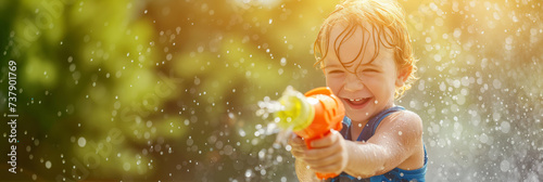 Happy child playing with water gun on hot summer day. Cheerful child having fun with water toys. Leisure for young children in summer.