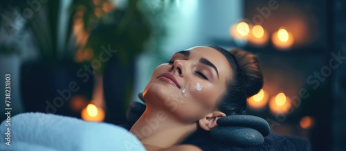 Relaxed woman receiving hot stone massage in modern spa salon.